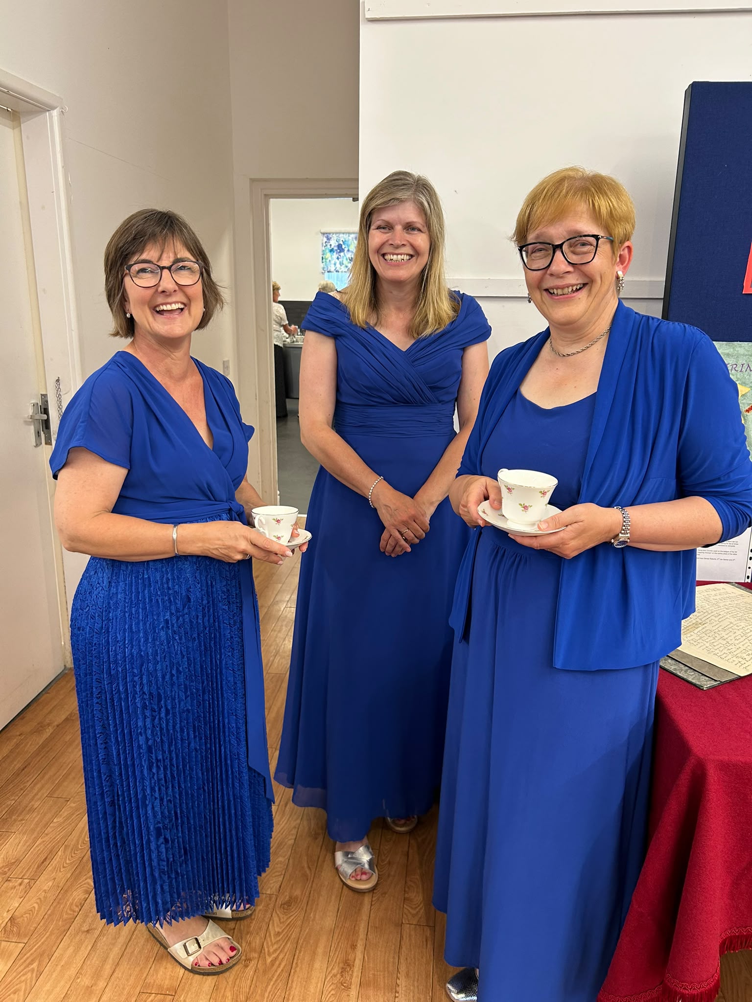 Choir members chatting and holding teacups during a break.